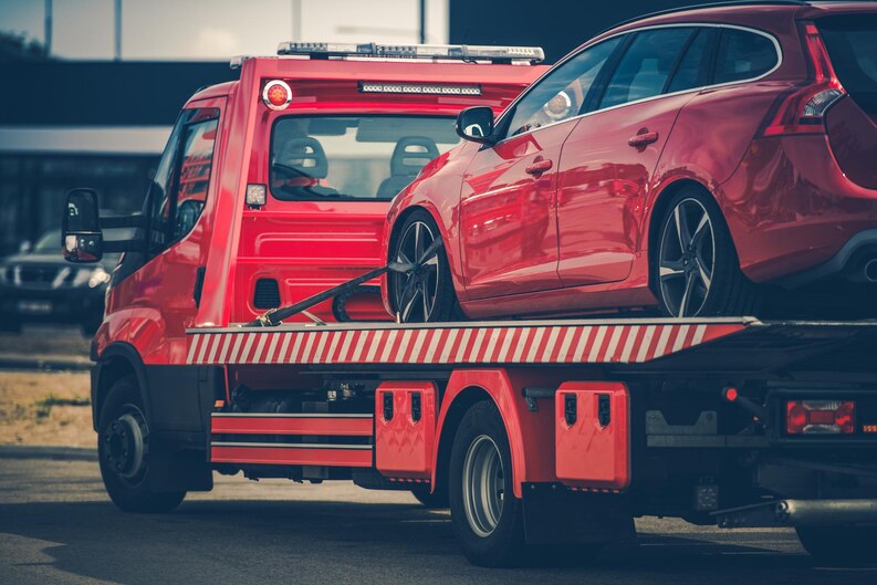 A red sports car is loaded onto a flatbed tow truck for recovery. The towing service is assisting with the breakdown, ensuring safe transport of the vehicle. Our company provides professional car recovery services, quickly and efficiently recovering broken-down vehicles in Dubai